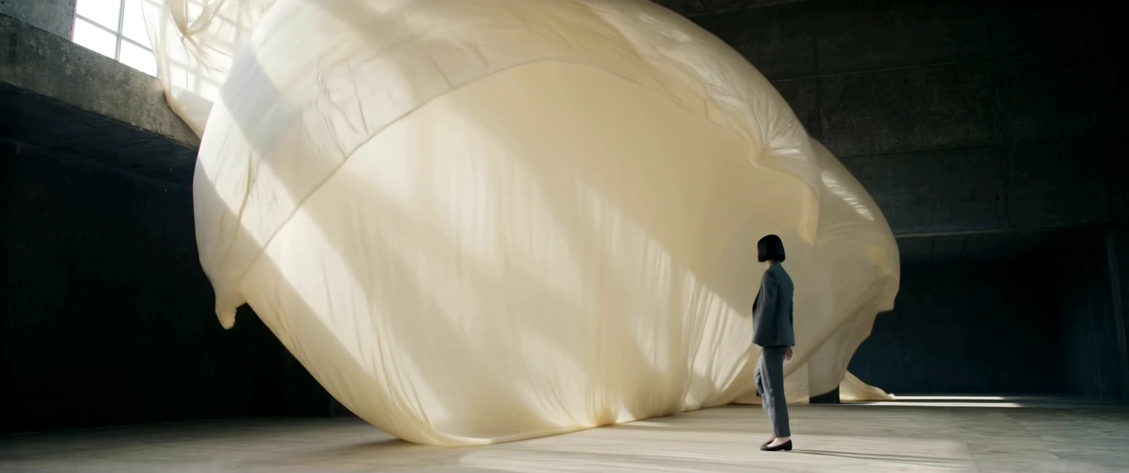A lone figure faces a monumental floating cloth in Still Mine